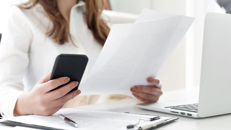 femme regardant téléphone et papier