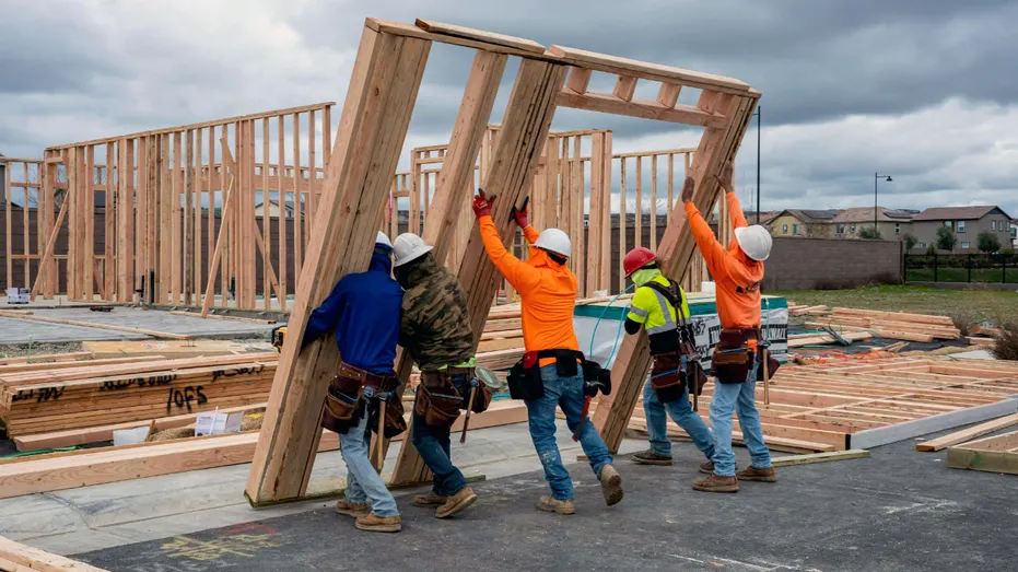 Les constructeurs soulèvent les charpentes en bois qui font partie d’une maison.