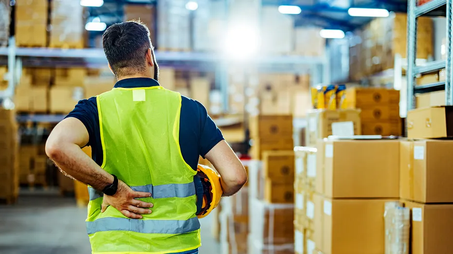 Un employé d’entrepôt est photographié à côté des cartons.