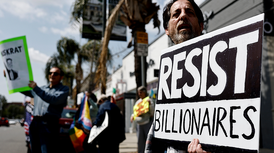 Personne brandissant une pancarte « Résistez aux milliardaires »