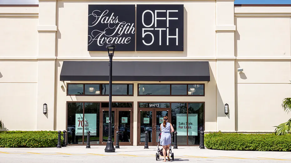 Une femme se dirige vers le magasin Saks OFF 5TH en Floride