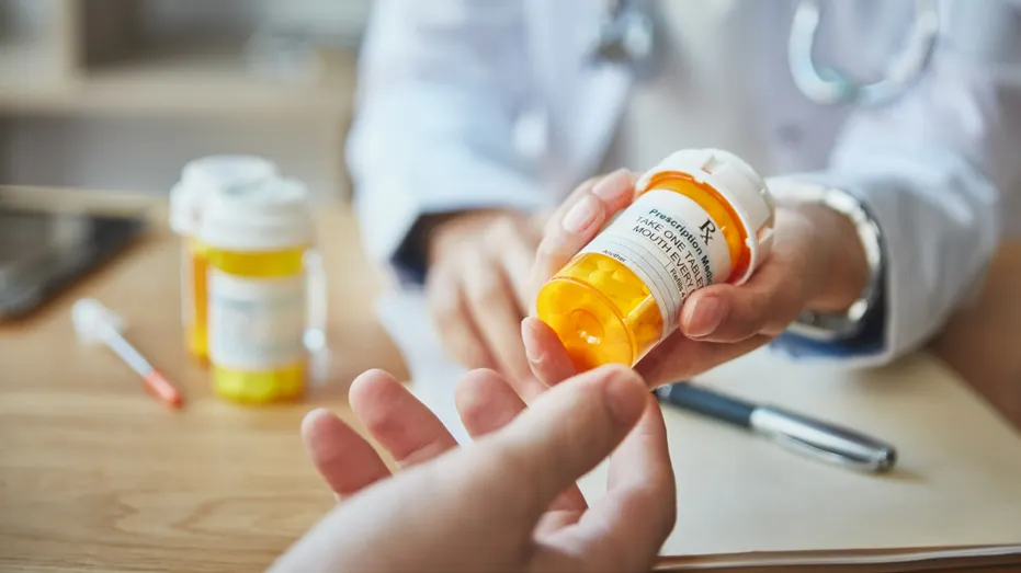 Un pharmacien remet à un patient une bouteille de médicaments sur ordonnance.