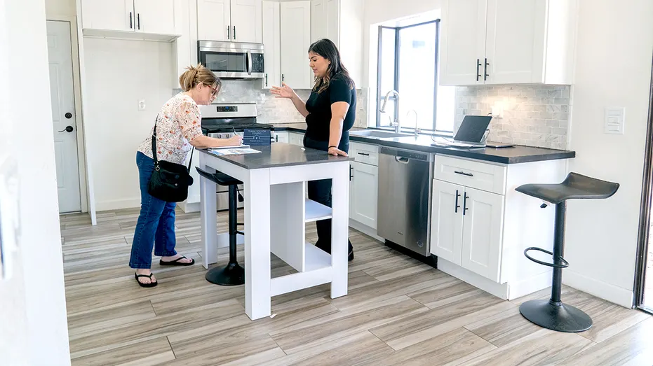 Un agent immobilier discute avec un client dans une maison.