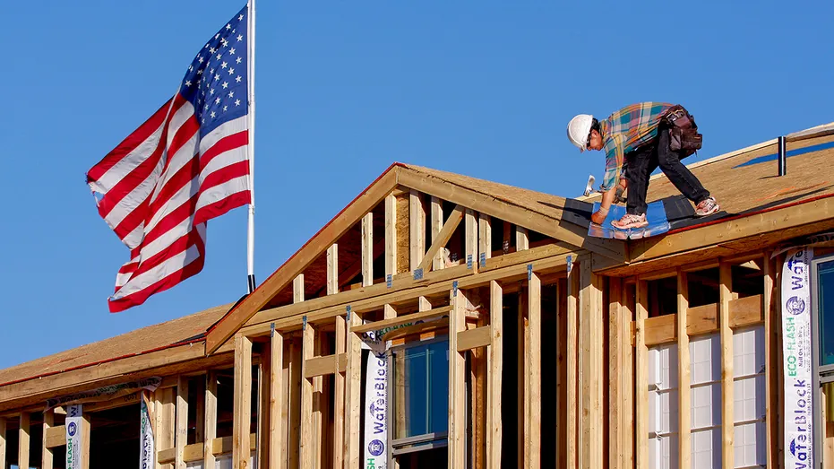 Les ouvriers du bâtiment construisent une maison avec le drapeau américain en arrière-plan