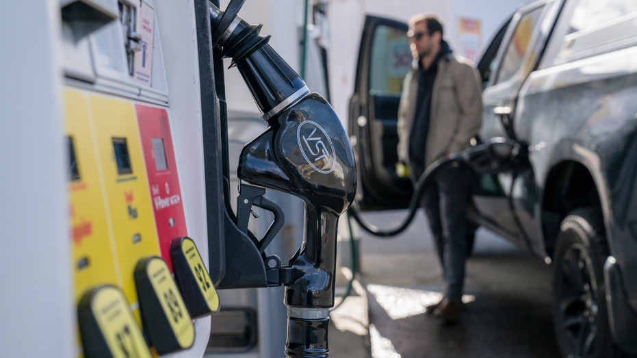 On voit un homme pomper de l’essence dans son camion dans une station-service.