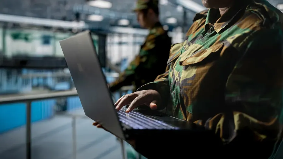 Gros plan d'un employé du hub de serveur en uniforme de soldat tapant sur un ordinateur portable