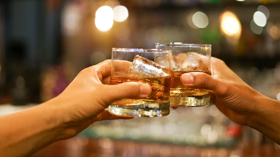 deux hommes trinquant des verres de whisky boivent de l'alcool ensemble au comptoir du pub