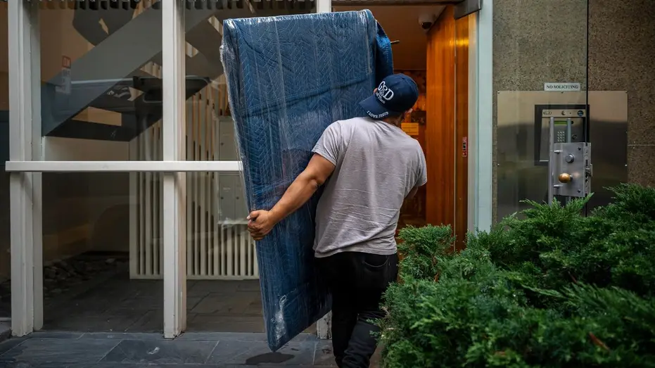 un employé déplace la télévision dans son appartement
