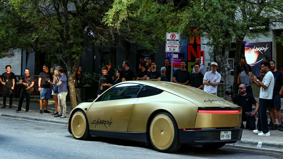 Les gens regardent un Tesla Cybercab doré arriver pour un événement au centre-ville d'Austin, au Texas.